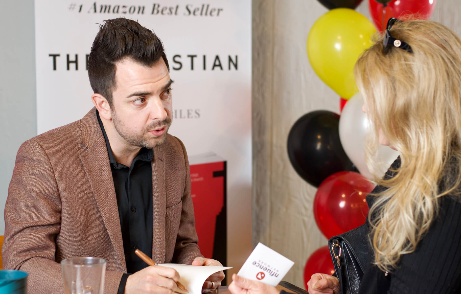 Lucas Miles signing his book while speaking with the purchaser